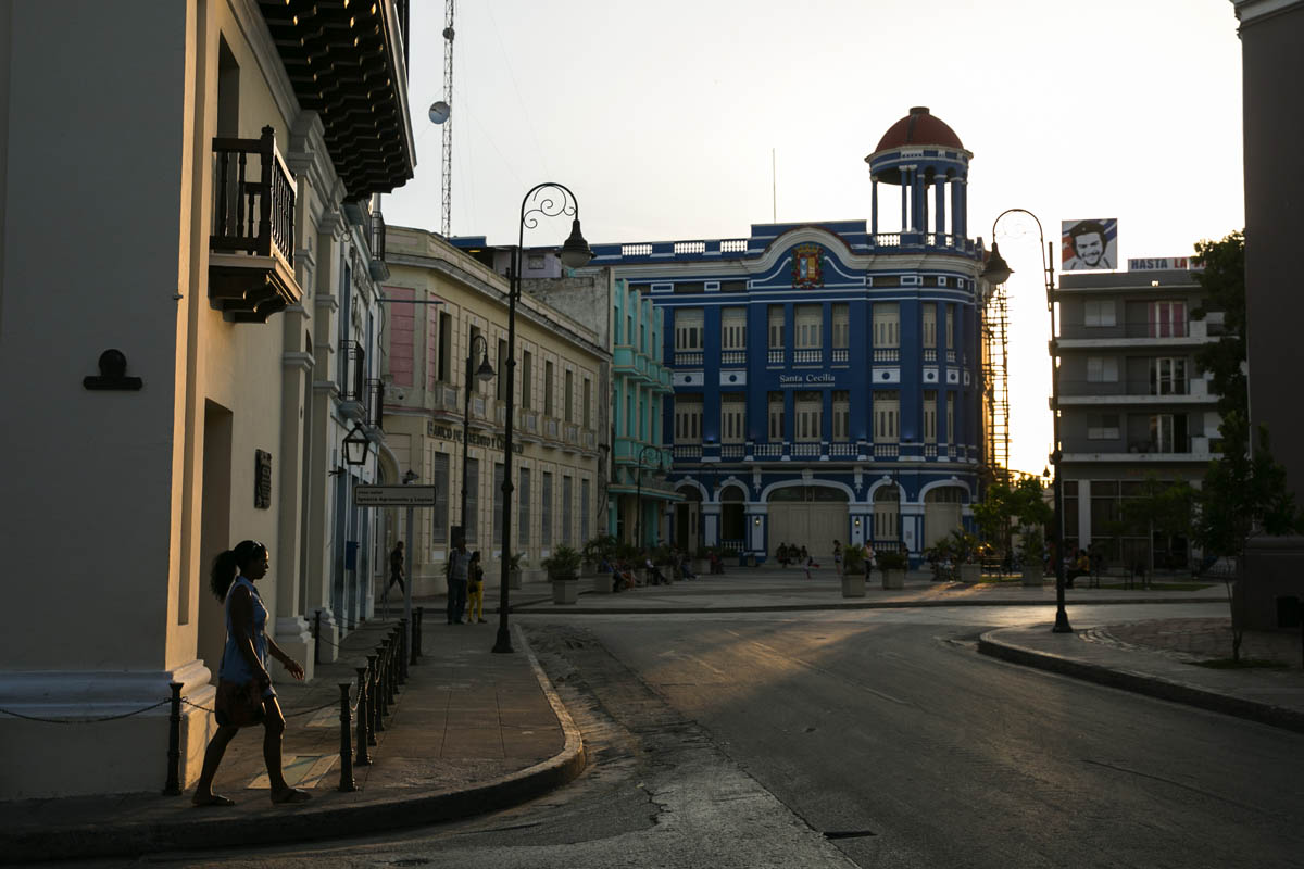 Sunset illuminates a woman walking toward the Plaza de los Trabajadores, Camagüey, Cuba.