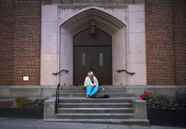 Milee Ballweg, 20, sits on the steps of a church in the University District where she sleeps just after 5:00 a.m. on Wednesday, July 11, 2018, in Seattle. Minutes before, a friend who lives in a nearby building yelled loudly to wake her up and alert her that a man was standing over her as she slept. KUOW Photo/Megan Farmer