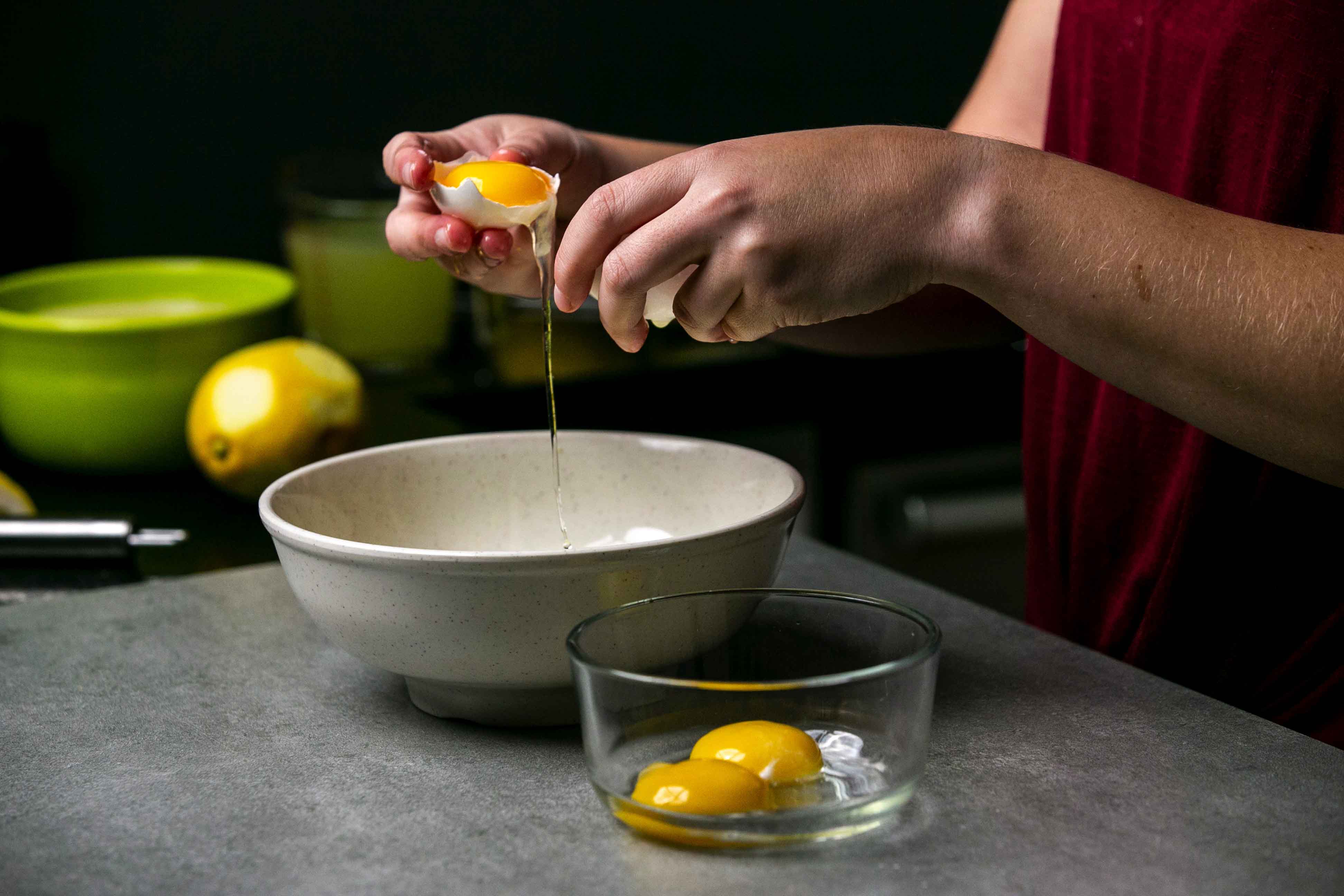 Separating an egg yolk from an egg white above a white bowl.