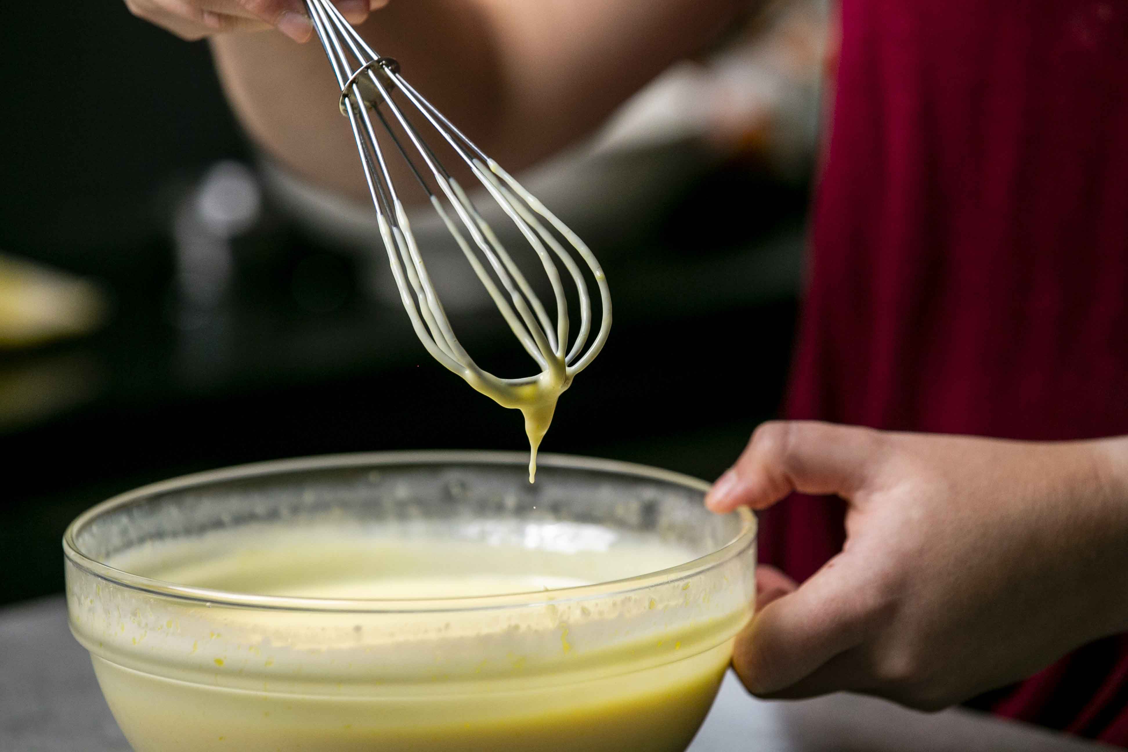 Whisking together the ingredients for the lemon filling in a clear bowl.