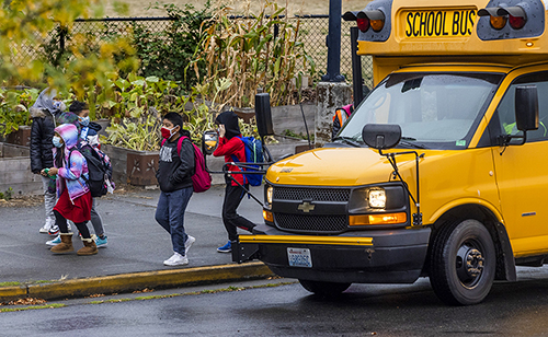 Students pass a school bus after being dropped off Sept. 17, 2021 at Rising Star Elementary School. (Daniel Kim / The Seattle Times)