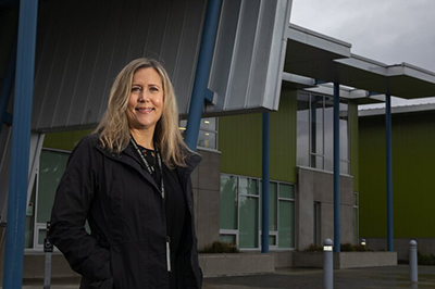 McMicken Heights Elementary School Principal Alexandria Haas stands in front of her SeaTac school Tuesday, Dec. 15, 2020. She has overseen the school’s experiment in acceleration, which seeks to combat learning loss before it happens by boosting students along and helping them fill in the gaps of what they missed. The Highline school district is trying to avoid learning loss by boosting students ahead. (Ellen M. Banner / The Seattle Times)