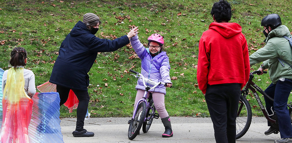 Foster mom Karla Petersen high-fives Elizabeth, 8, after her first bike ride without training wheels. Petersen used this difficult time to encourage her seven kids learn at their own pace. (Ken Lambert / The Seattle Times)