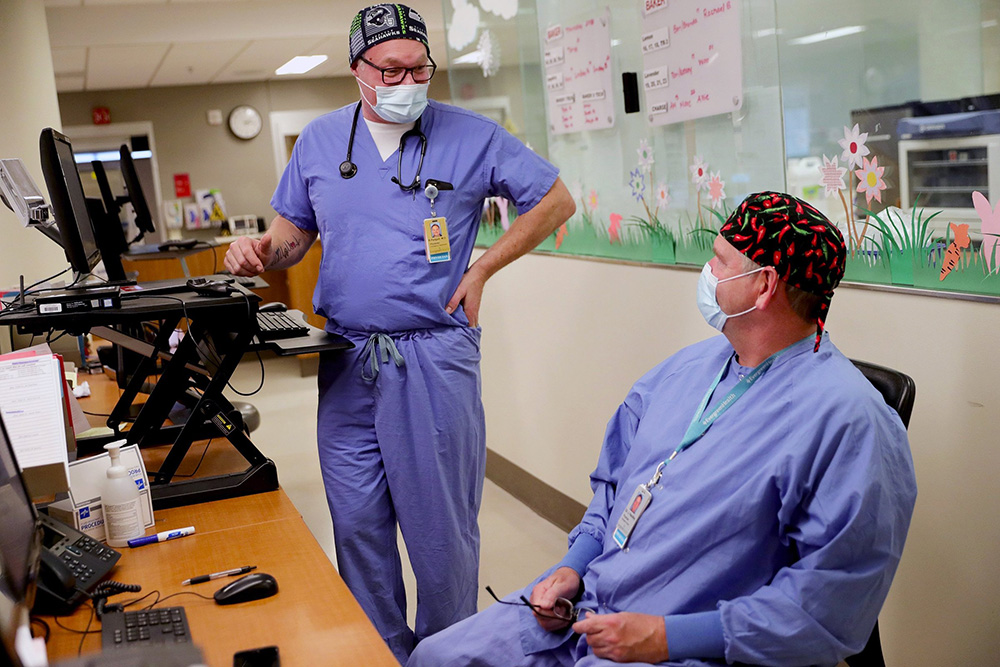 Back at work, Dr. Ryan Padgett, left, talks with Dr. Jack Handley in the emergency department at EvergreenHealth in Kirkland on Feb. 11, 2021. (Erika Schultz / The Seattle Times)