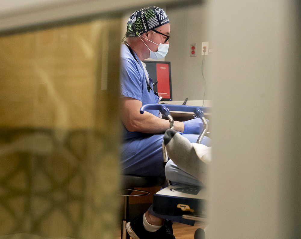 Dr. Ryan Padgett works with a patient in the emergency department at EvergreenHealth in Kirkland. (Erika Schultz / The Seattle Times)