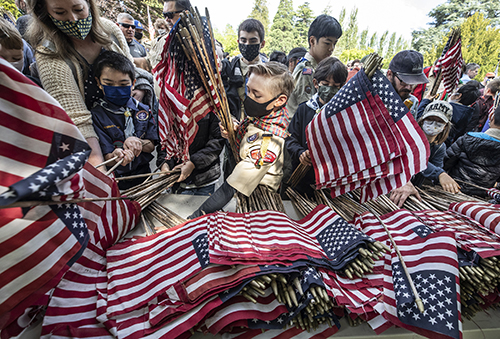 Chaos ensues when Boy Scouts rush to pick up ceremonial flags at the 95th Memorial Day ceremony at Washelli Memorial Cemetery, and Jared Petras, 10, is in the center of the scrum. Knowing I’d be run over by the Scouts, I positioned myself on the other side of the table as the rush began. Each of the cemetery’s 5,000 white, upright marble markers received a flag placed by Scouts, community members and veterans.