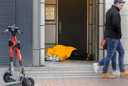 I got a call from Seattle Times photo editor Fred Nelson, assigning me to find a homeless scene for the next day’s paper. Parking downtown, I spotted this person sleeping in an alcove near Westlake Park. The person’s face was covered, and the blanket was bright yellow, which separated it from the background. I waited for pedestrians walking by, seemingly not noticing the sleeping person. I used a Canon 70-200 mm lens, standing across the street.