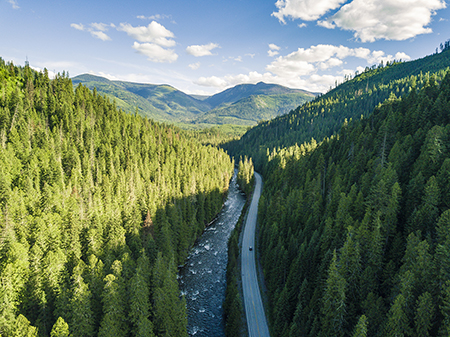 a car drives through a sweeping landscape of mountains in the Idaho Countryside.