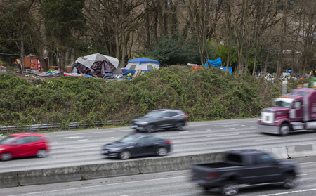 Traffic on Interstate 5 whizzes past tents near North Seattle College in April. (Ellen M. Banner / The Seattle Times)