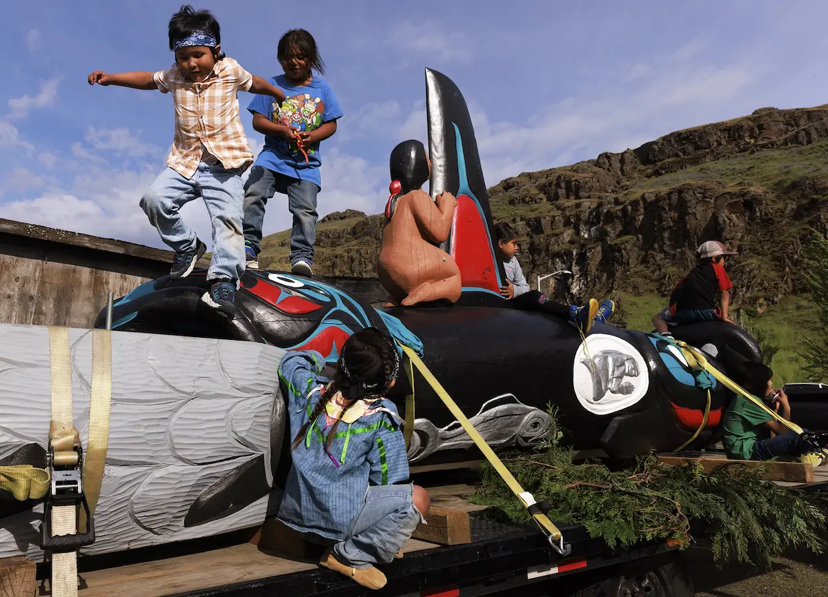 Victor Jim, 6, left, and Cody Meanus, 8, play atop a totem pole at the Celilo Village longhouse. The pole, carved by Jewell James of the Lummi Nation, is part of the Spirit of the Waters journey, a Native-led movement for the removal of four Lower Snake River dams to rebuild salmon runs and to help the southern resident killer whales. The photo of Victor and Cody published as part of the immersive project “First Foods: How Native people are revitalizing the natural nourishment of the Pacific Northwest.