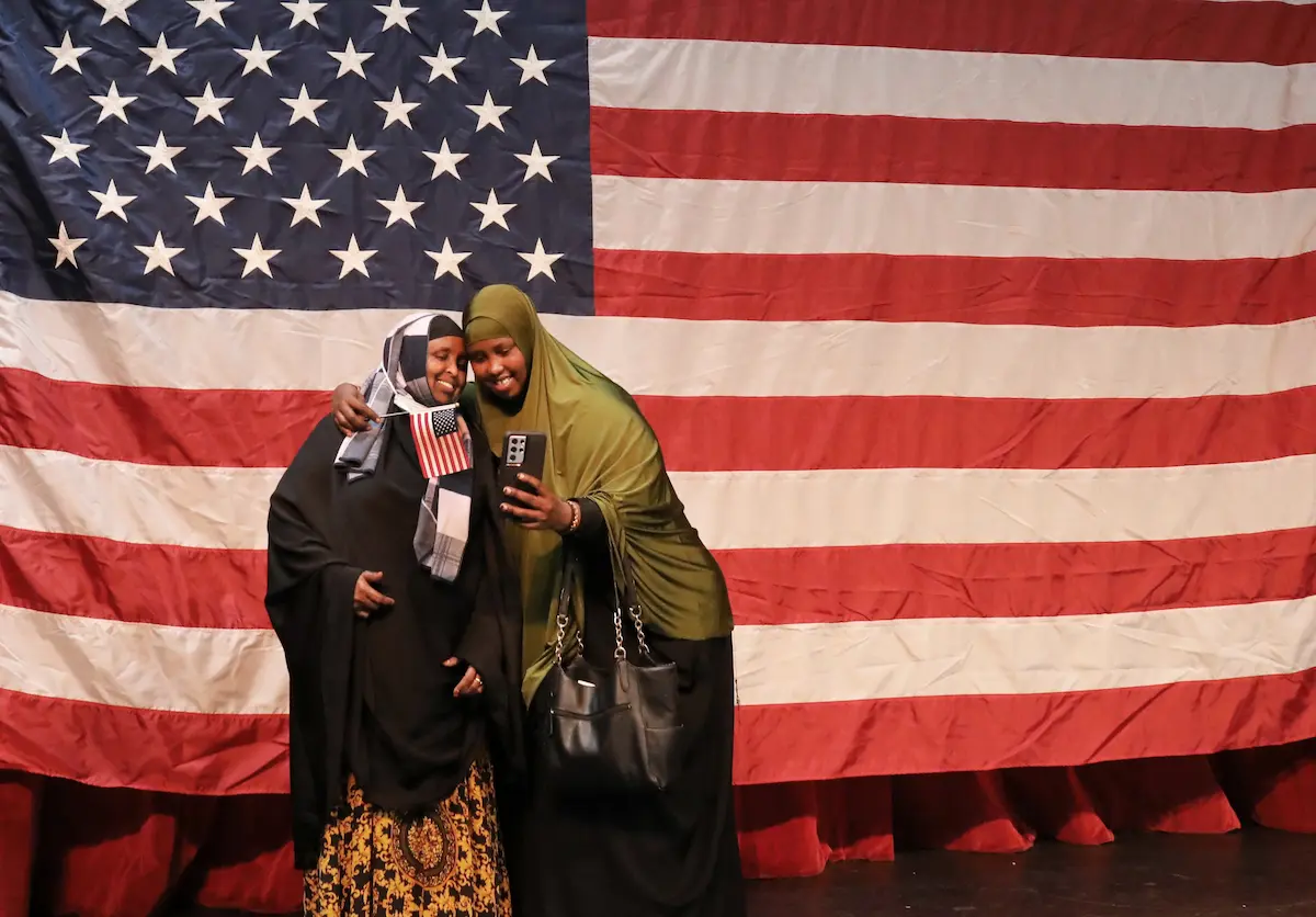 Brimming with pride, new citizen Badra Hirsi from Somalia photographs herself and her cousin Hodo Mohamed in front of the giant Stars and Stripes in the Seattle Center Armory on the Fourth of July at the annual naturalization ceremony, one of our great local events. This year, 293 people from 74 countries became citizens. As the name of each country is read, the new citizens stand to applause from family, friends and local officials. Mohamed already was a citizen.