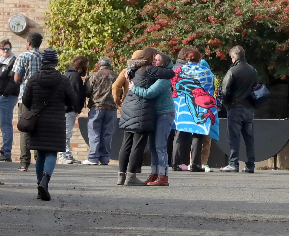 Parents comfort each other outside Ingraham High School after the report of a shooting. I watched parents gathering outside the school building, waiting for word, for several minutes, then two women hugged. I used a 70-200 mm lens;this photo was taken from about a block away.