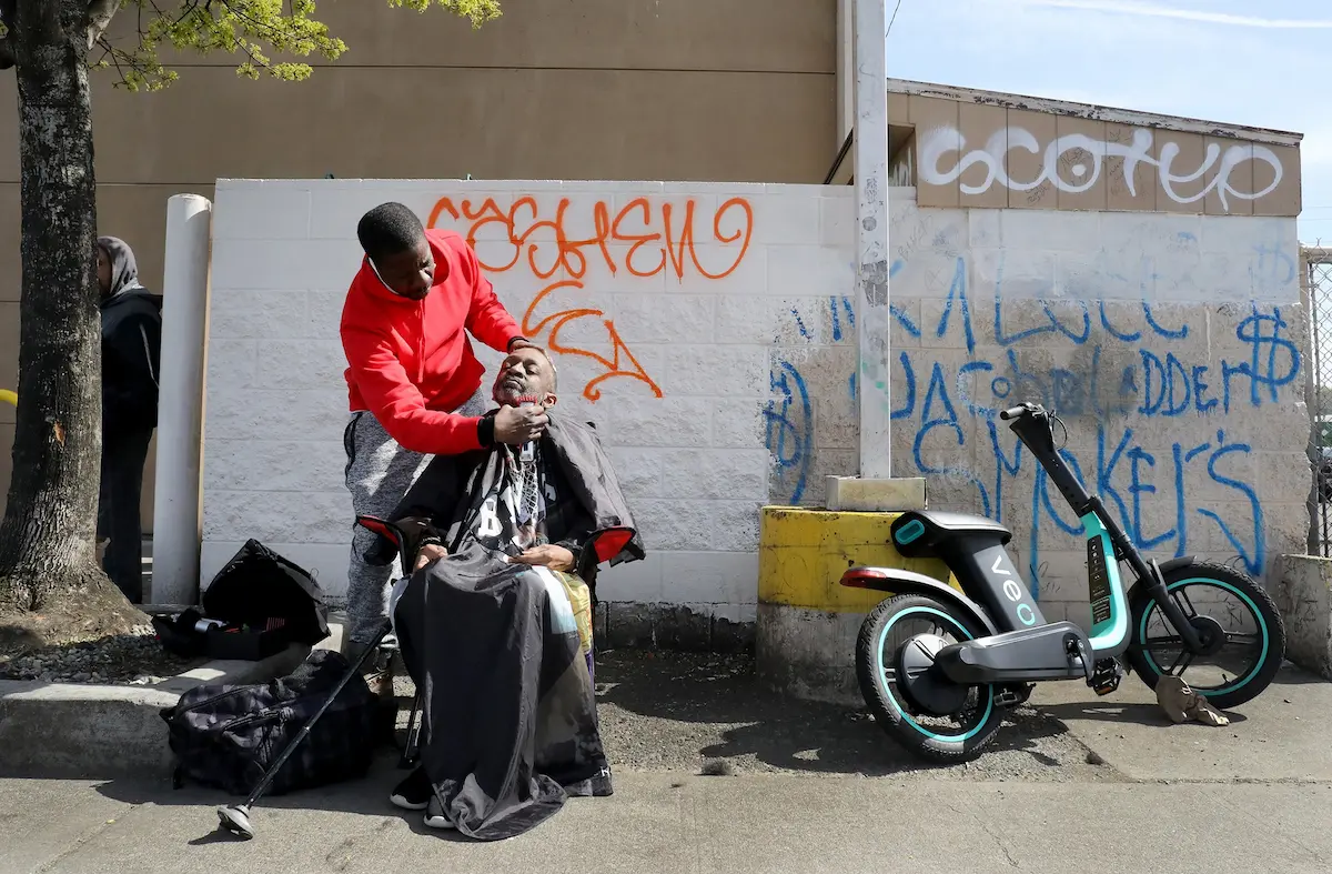 Carrying a folding chair and battery-powered clippers, Randy Miller gives free haircuts on the streets of Seattle including Richard Banks on Fourth Avenue South in Sodo. Writer Anna Patrick found Miller living in a shelter. The recipients like their haircuts and sometimes give a tip of a dollar or two.   Miller does not have a barber's license and could use a scholarship to barber college.